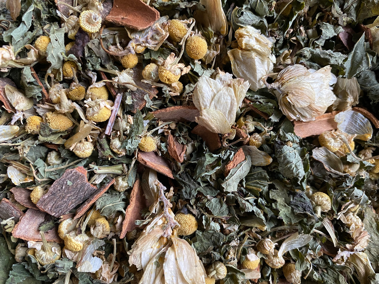 Good Night loose-leaf blend seen from overhead — chamomile flowers and cinnamon bark among the dried herbs.