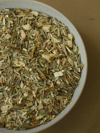 Good Morning loose-leaf blend — pale lemongrass strands and dried ginger in a stoneware bowl, closely observed.
