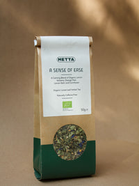 A Sense of Ease loose-leaf herbal tea — blue cornflower petals and dried herbs visible through the kraft pouch window.