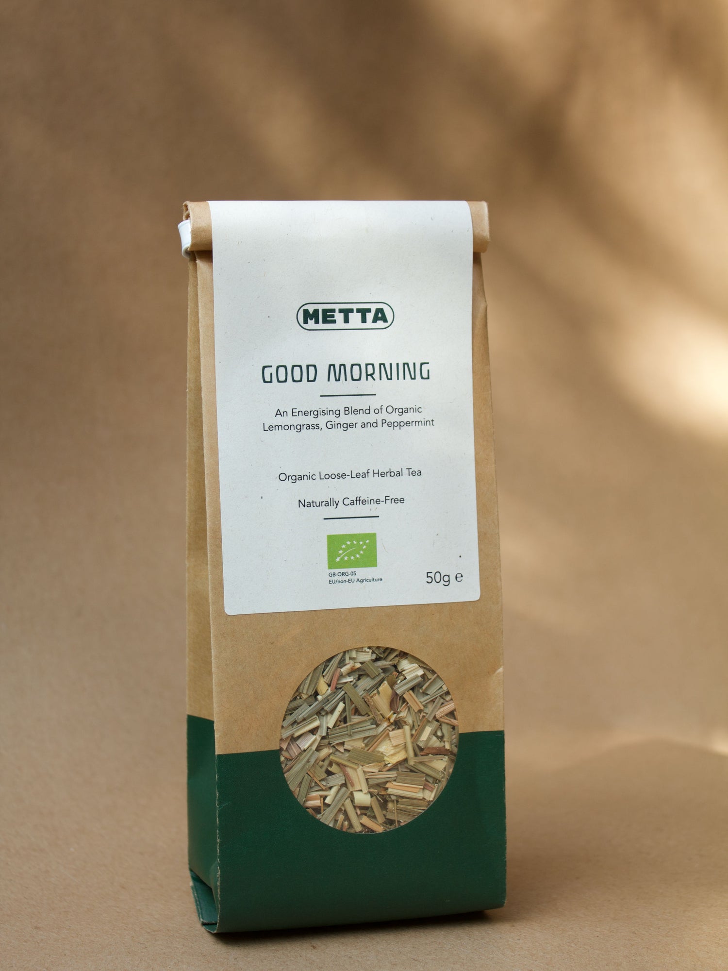 Good Morning loose-leaf herbal tea — pale lemongrass and ginger pieces visible through the kraft pouch window.