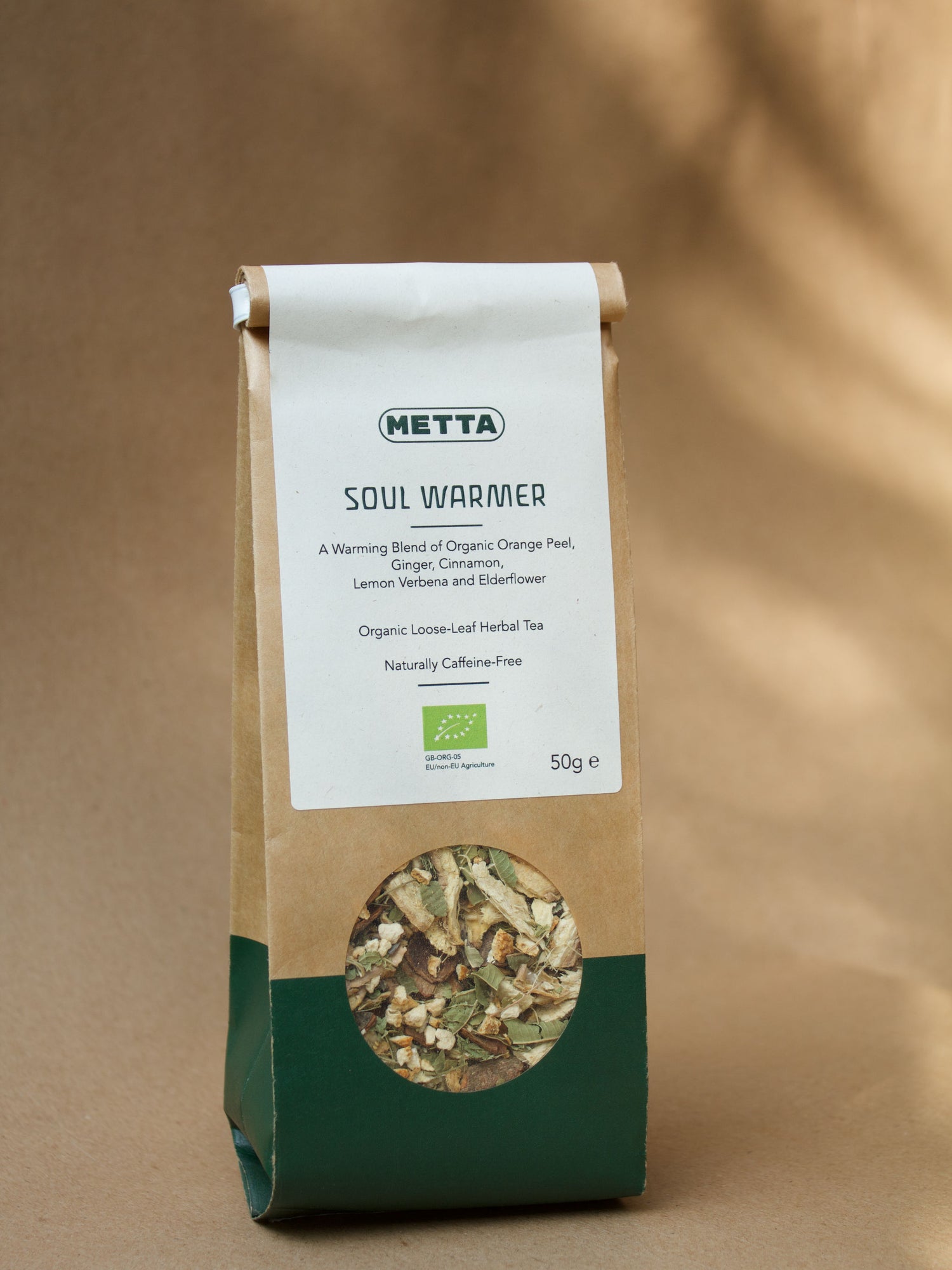 Soul Warmer loose-leaf herbal tea — orange peel, ginger and cinnamon visible through the kraft pouch window.