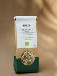 Soul Warmer loose-leaf herbal tea — orange peel, ginger and cinnamon visible through the kraft pouch window.