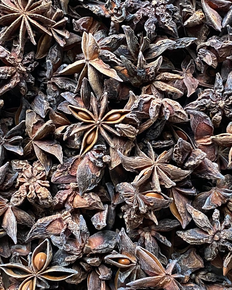 Dried whole star anise pods scattered closely — a study in deep brown stars and seedpods.